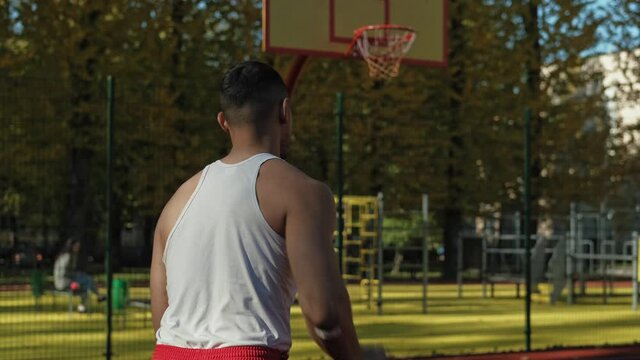 African american player throwing ball. Back view of young man training outdoors. Man playing basketball in slow motion. Sport concept. 4K, UHD