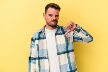 Young caucasian man isolated on yellow background showing thumb down, disappointment concept.