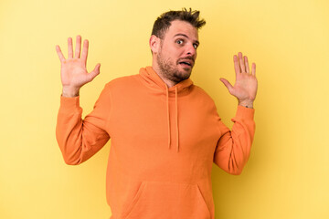 Young caucasian man isolated on yellow background being shocked due to an imminent danger