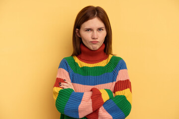 Young English woman isolated on yellow background frowning face in displeasure, keeps arms folded.