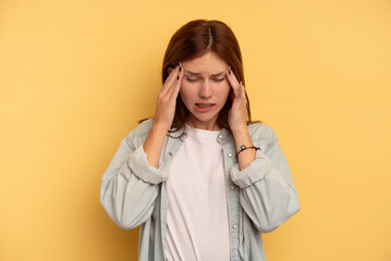 Young English woman isolated on yellow background having a head ache, touching front of the face.