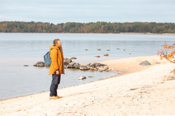 Caucasian man standing near the lake and enjoying the view. Man resting after a long walk