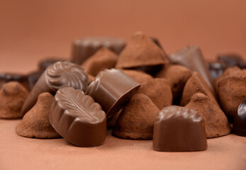 Chocolate pralines and truffles on a brown background stock images. Pile of chocolate truffles and candies isolated on a brown background stock images. Various chocolate candies close-up stock photo
