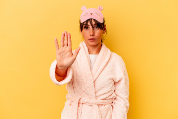 Young Argentinian woman wearing a pajama isolated on yellow background standing with outstretched...