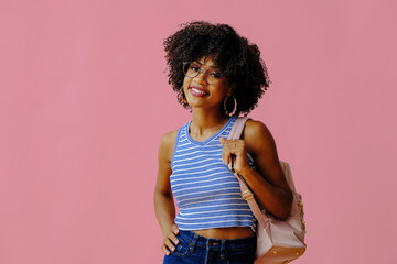 beautiful smiling girl in eyeglasses with backpack posing on pink background, back to school concept