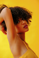 Obraz premium portrait of beautiful young African american woman in bright summer outfit posing isolated on yellow background