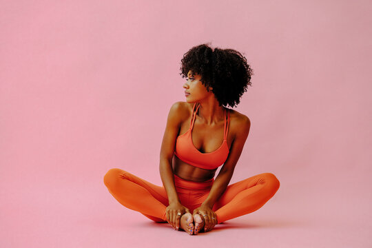 beautiful African american woman meditating in sports outfit on pink background