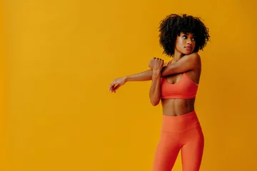 Tuinposter young fit black woman in sportswear posing isolated on yellow background © Carlos David