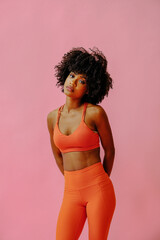 attractive young black african american adult woman in sports outfit looking at camera and posing isolated on pink background