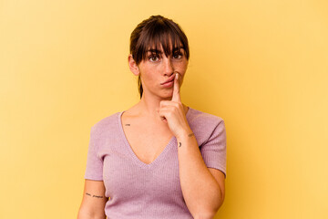 Young Argentinian woman isolated on yellow background thinking and looking up, being reflective, contemplating, having a fantasy.