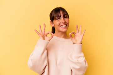 Young Argentinian woman isolated on yellow background cheerful and confident showing ok gesture.