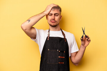 Young caucasian hairdresser man holding scissors isolated on yellow background being shocked, she...