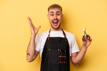 Young caucasian hairdresser man holding scissors isolated on yellow background receiving a pleasant...