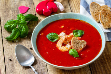 Homemade Valentine soup, festive food. Tomato soup puree gazpacho with tomatoes served seafood on a rustic wooden table.