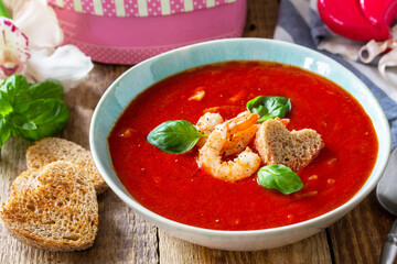 Homemade Valentine soup, festive food. Tomato soup puree gazpacho with tomatoes served seafood on a rustic wooden table.
