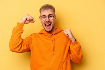Young caucasian man isolated on yellow background cheering carefree and excited. Victory concept.