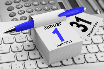 Deutscher Kalender Neujahr 2022  Samstag 1. Januar und PC Tastatur mit Rechner und Kugelschreiber
