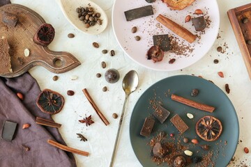 Black and milk chocolate, sweets, dried citrus fruits, coffee beans and spices on the table, top view, home cooking, sweet food