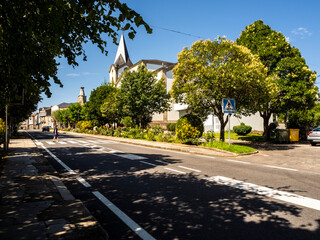 Fototapeta premium imagen de una carretera que cruza un pueblo con una iglesia de fondo y lleno de árboles