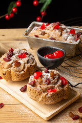 Aerial view of individual plum cakes, decorated with sugar, raisins and cherries, on rustic table, in vertical