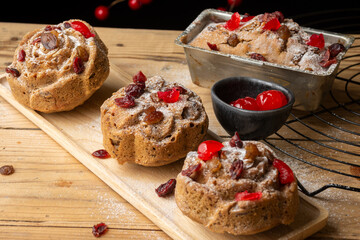 Top view of individual plum cakes, decorated with sugar, raisins and cherries, selective focus, on rustic table, horizontal