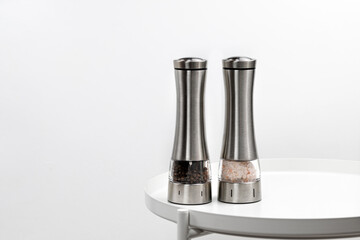 Two electric spice mills for salt and pepper. Metal. On a white table