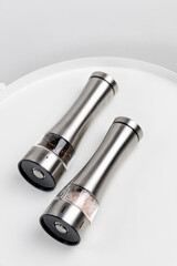 Two electric spice mills for salt and pepper. Metal. On a white table