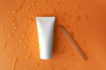 Top down view mockup facial skincare white tube propolis product with honey drop smear on plain...