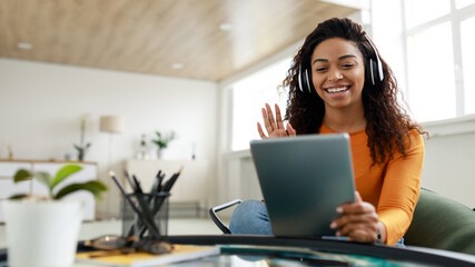 Black woman having video call using tablet and waving hand