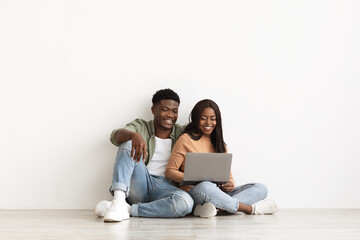 Happy black man and woman using notebook together