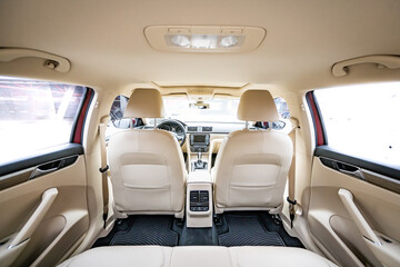 Car interior luxury. Beige comfortable seats, steering wheel, dashboard, climate control, speedometer, display, wood decoration light