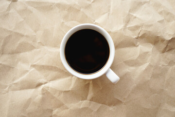 Flat lay view of black coffee cup on crumple brown paper