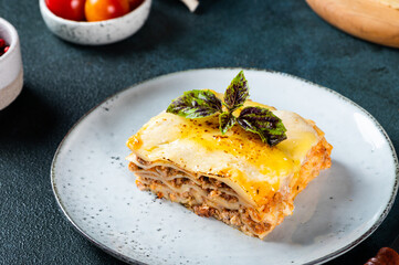 Piece of tasty hot lasagna on dark background. Traditional italian lasagna. Italian food. Close up lasagna. Bolognese sauce. Bechamel sauce. Still life of food. Homemade meat lasagna.