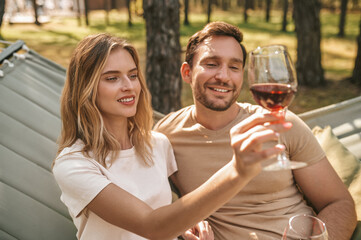 Young smiling couple holding glasses with wine and looking happy