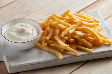 Hot golden french fries with sauce on wooden background. Homemade rustic food.
