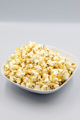 Popcorn on a white background. Fresh popcorn in ceramic bowl. Close-up. Vertical view
