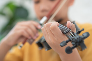 A Little Asian kid playing and practice violin musical string instrument against in home, Concept of Musical education, Inspiration, Teenager art school student, Selective focus.