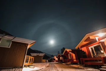 Foto op Aluminium The halo effect of the moon in the northern Norwegian city of Tromso among the red typical huts. A moon sighting. far beyond the Arctic Circle © Fauren