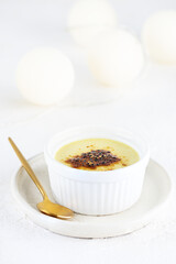 Homemade creme brulee in a white bowl on a wooden table. Sugar, gluten and lactose free and vegan.