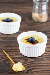 Creme brulee with blueberries in bowls on a wooden table. Sugar, gluten and lactose free and vegan.