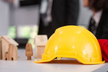 Yellow hard hat on desk worker team meeting background