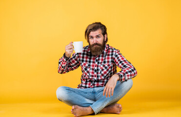 handsome bearded guy with unshaven face and stylish hairdo wear casual clothes drink coffee, cheers