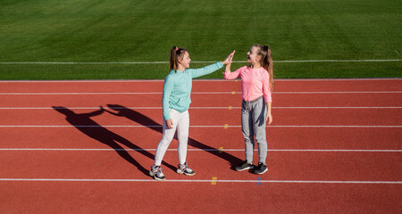 Obraz premium Having a little break. having fun. teen girls warming up on stadium. kids in sportswear take five. children relax after exercise on racing track. healthy childhood. workout on fresh air outdoor