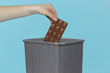 Throwing chocolate into trash bin, shekolade in hand in front of trash bin, diet concept, refusal...