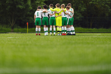 Soccer huddle. School boys standing together united in a team. Elementart age kids in sport team standing in circle on grass field