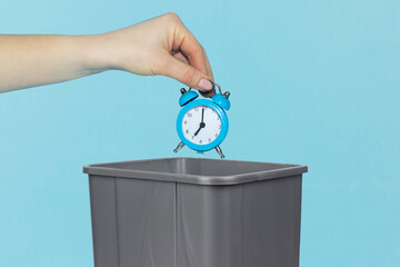 Throw alarm clock in trash bin, alarm clock in hand in front of trash bin, bad morning concept