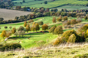 Golf course and golfers seen from high on a hill in rural setting 