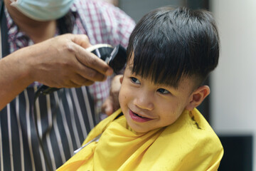 Asian boy getting haircut by professional barber