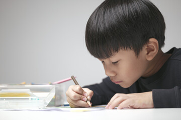 Asian boy about 5 years doing his homework, drawing and painting picture with color pencil.