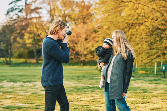 Photographer taking film pictures of young moder with toddler girl in autumn or spring park